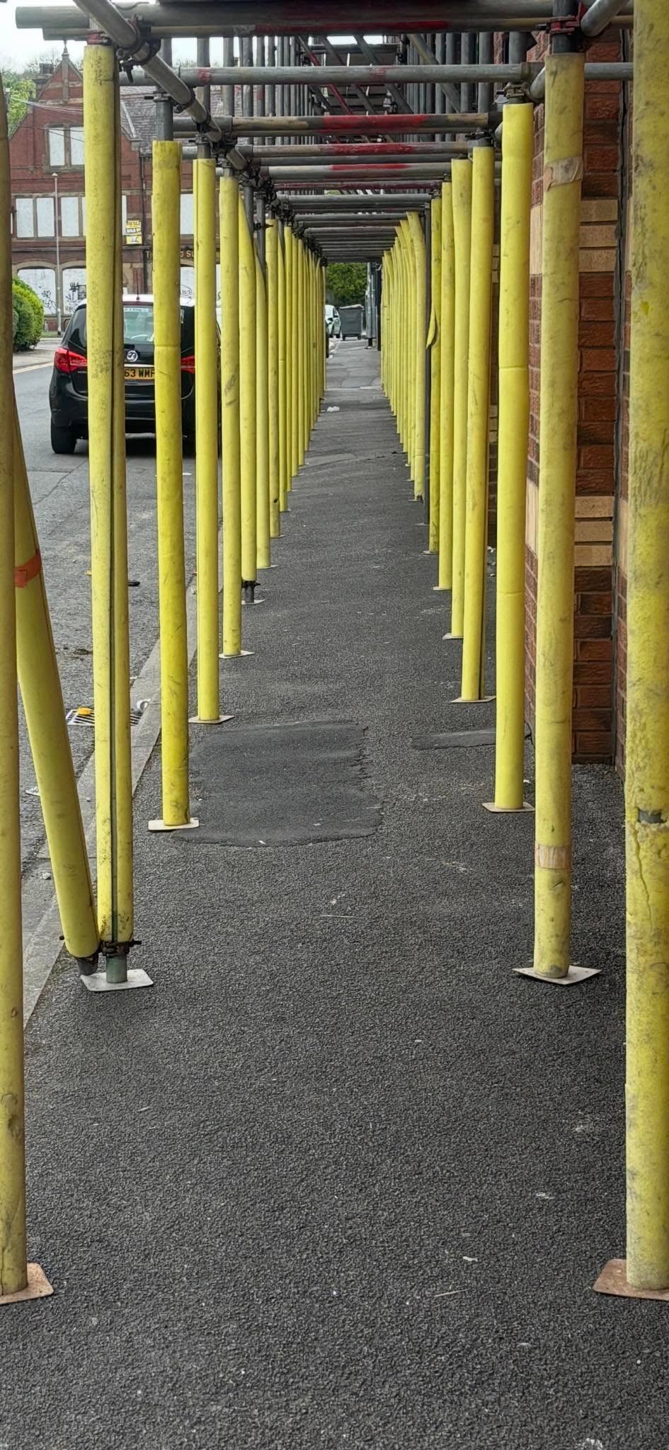Covered pedestrian walkway and gantry built from scaffold poles to protect the public
